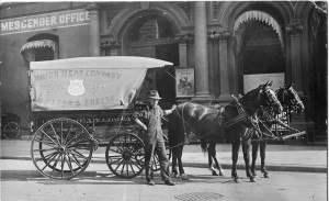 A Union Meat Company deliveryman in a jaunty pose with his team. The horses wear Teamster emblems on their headgear. 1910